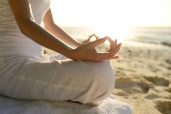 Women sitting on the beach practising yoga.